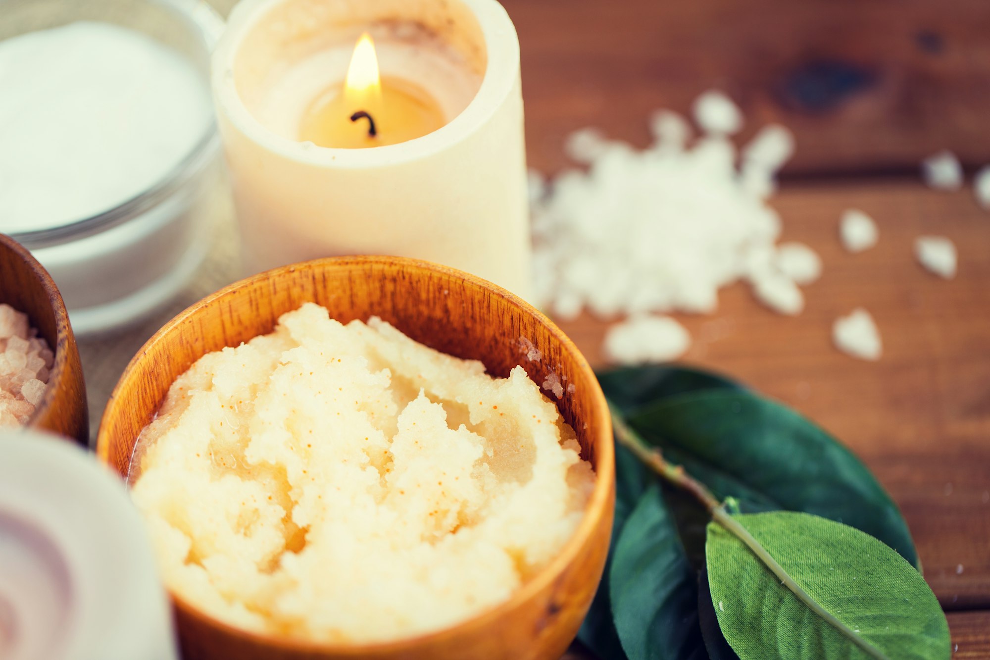 close up of natural body scrub and candle on wood