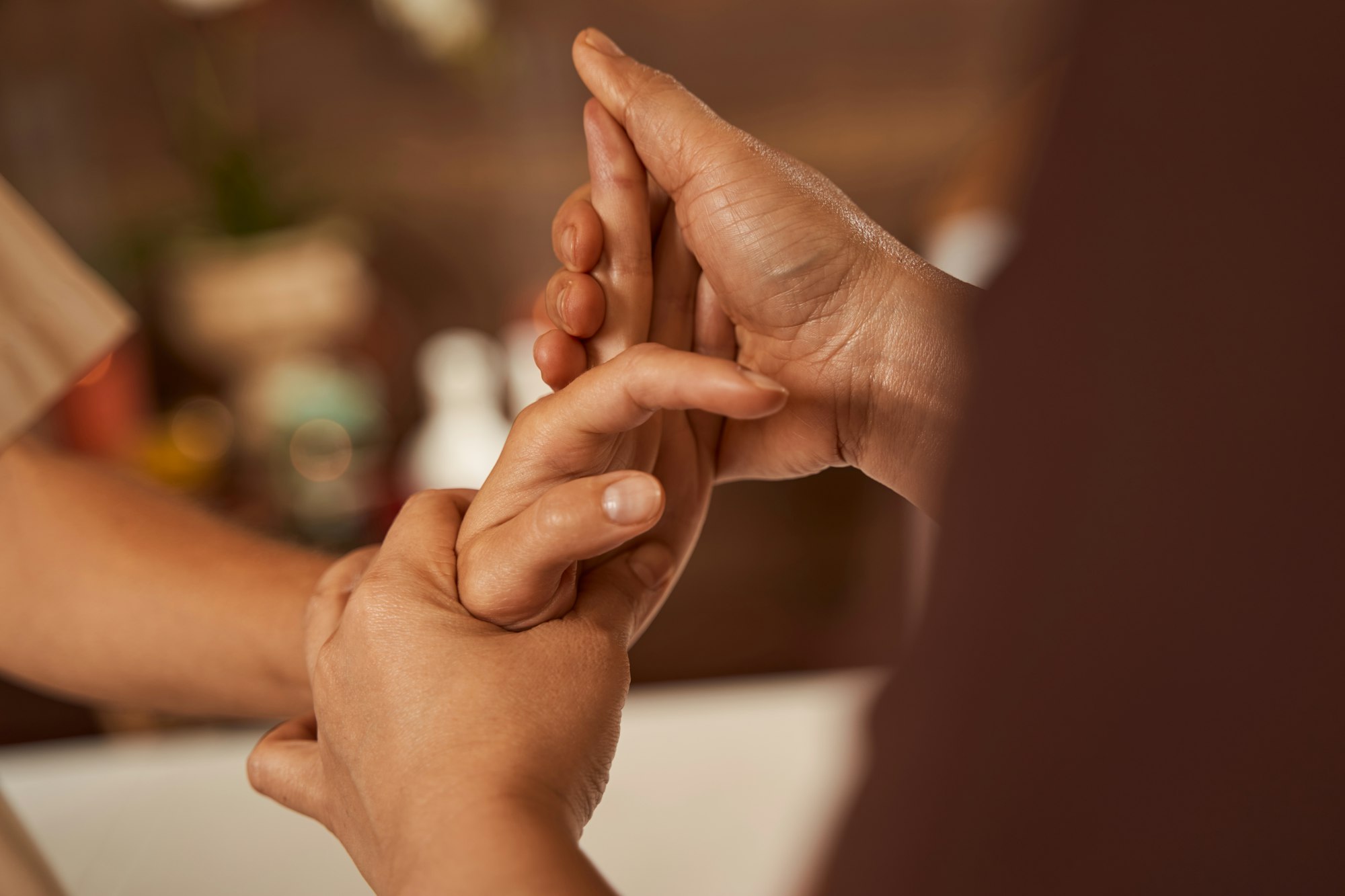 Masseuse stretching client fingers during hand massage session